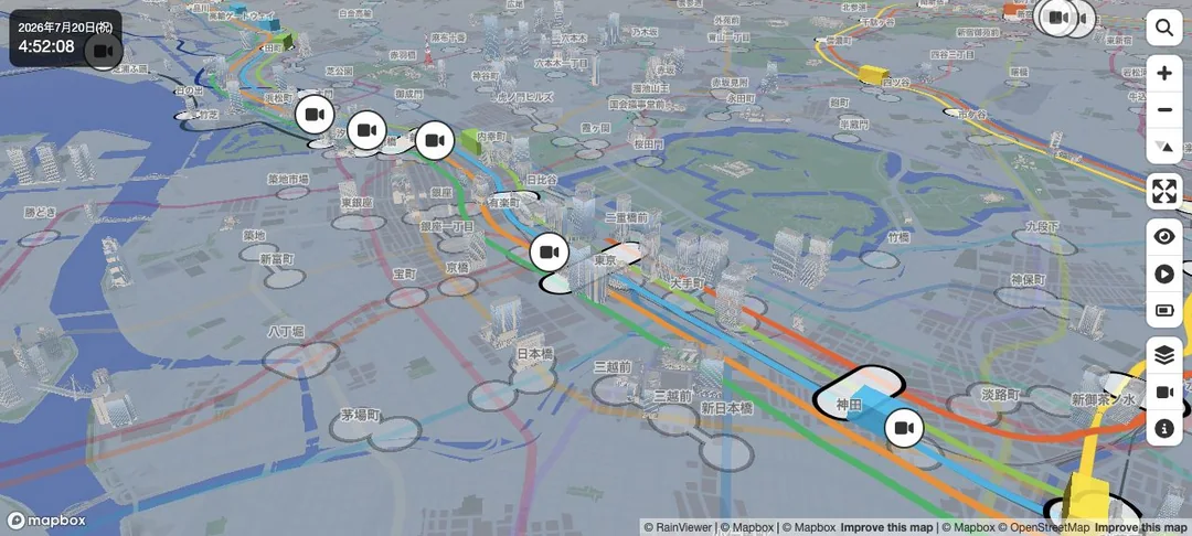 Mini Tokyo 3Dをカメラで斜めから見た3D表示。東京駅・日本橋・神田周辺の3Dビル群と、色分けされた鉄道路線が立体的に走る。遠景に東京タワー・六本木方面が見える